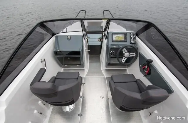 Interior view of a modern boat with two black seats, navigation console, and a panoramic windscreen overlooking the water.